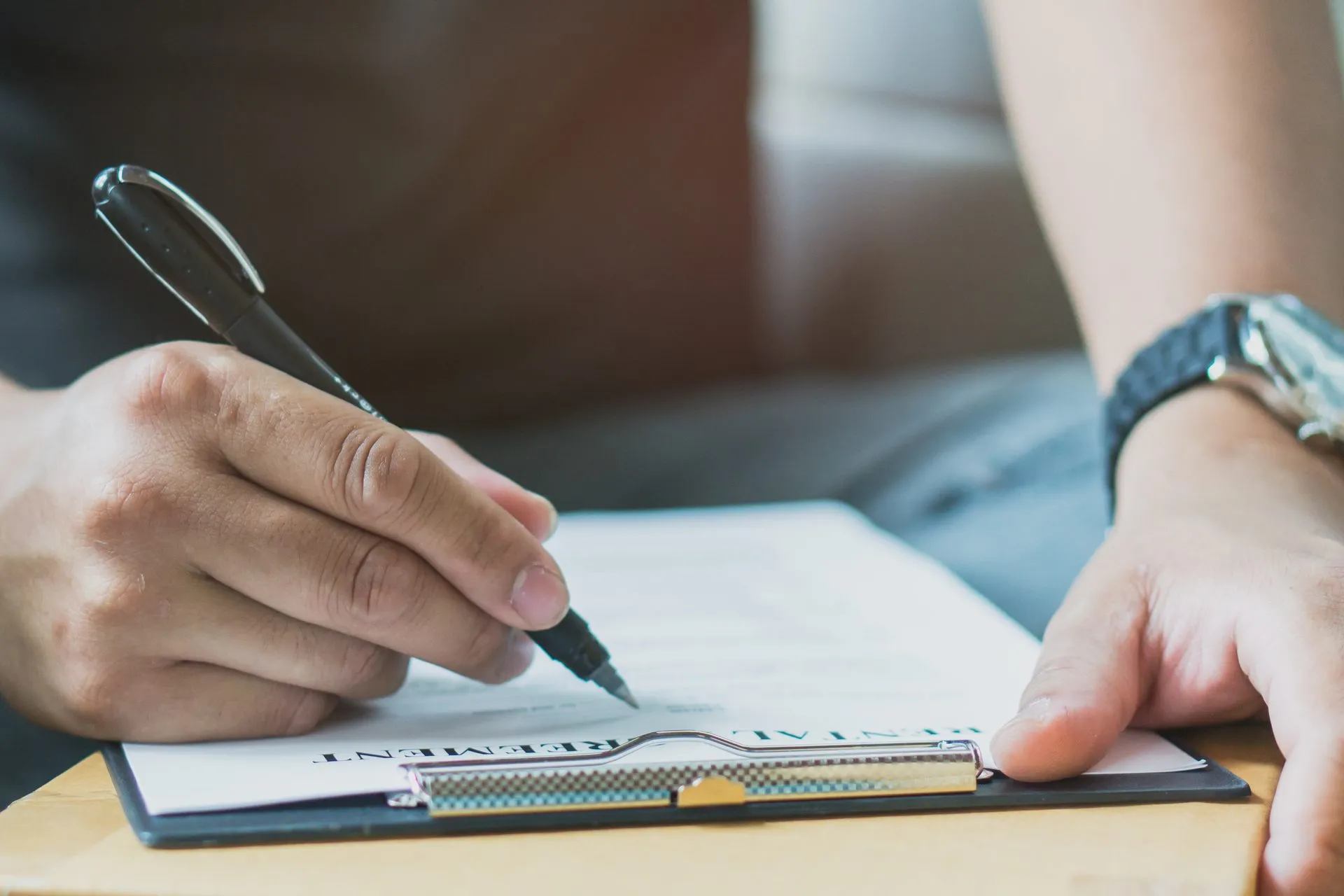 Primer plano de una persona que firma a mano un formulario de solicitud de inmigración antes de presentarlo ante el USCIS